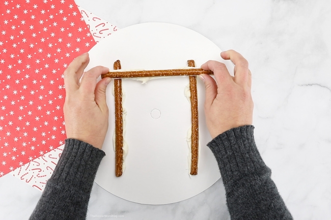 building a log cabin with pretzel rods and frosting