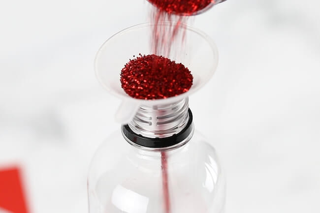 adding red glitter to water bottle
