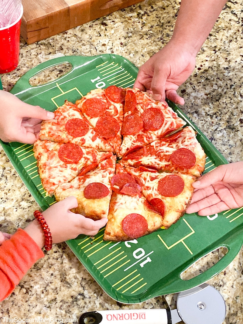 DiGiorno pepperoni pizza on counter with hands reaching to grab a slice