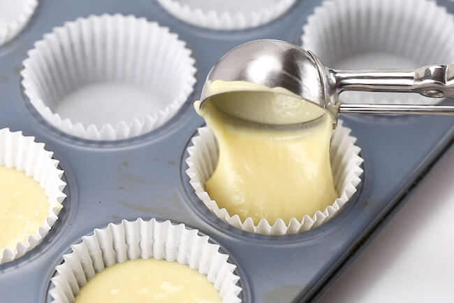 scooping champagne cupcakes batter into muffin tin