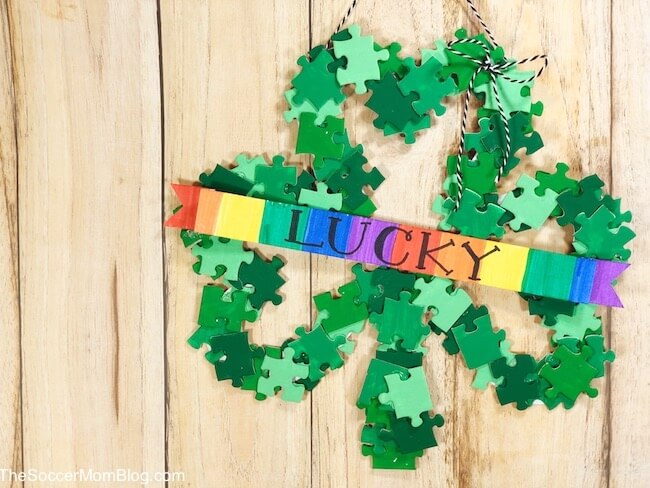 Add a lucky touch to your St. Patty's Day decor with this super cute DIY Shamrock Wreath! All you need is a dollar store puzzle, a recycled cardboard box, and simple art supplies! 