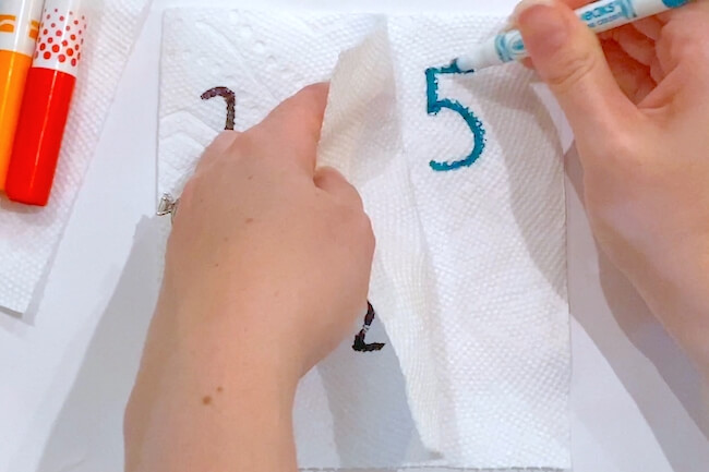 writing math problems on paper towel with markers