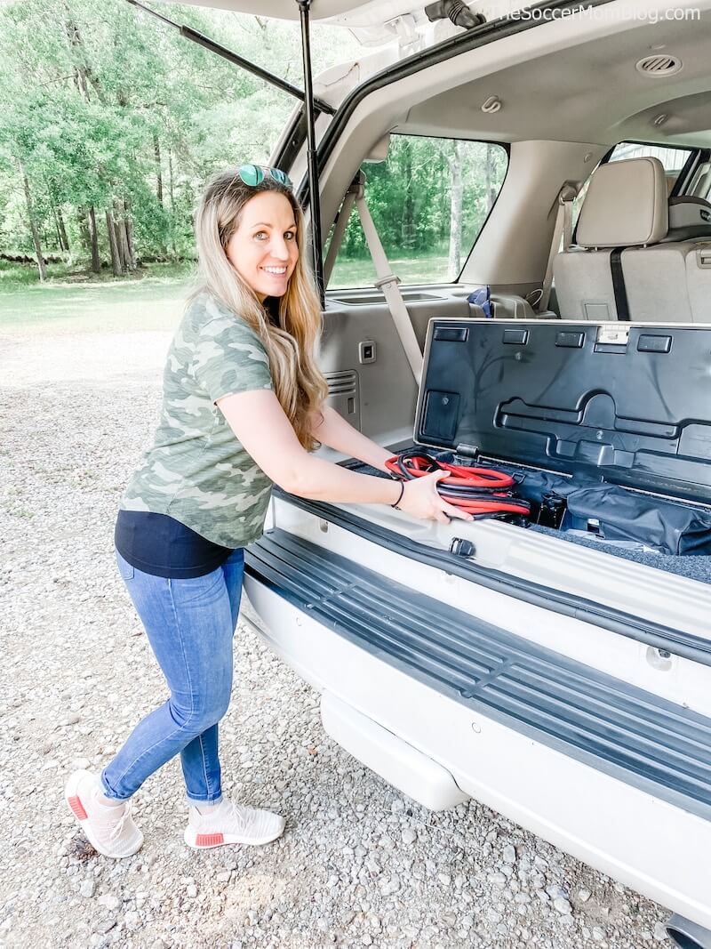 woman packing jumper cables in car trunk