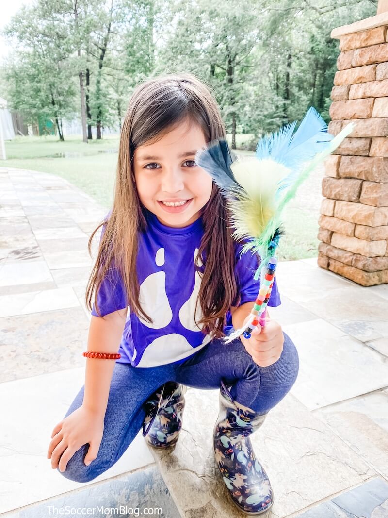 little girl in camp t-shirt holding a spirit stick