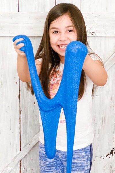 little girl playing with blue kinetic sand slime