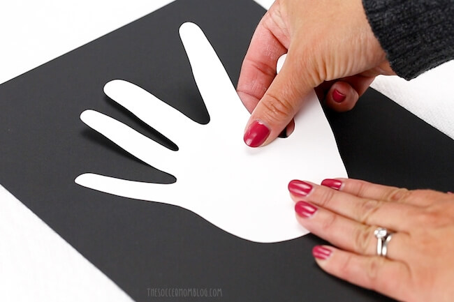 taping kids handprint to black paper paper