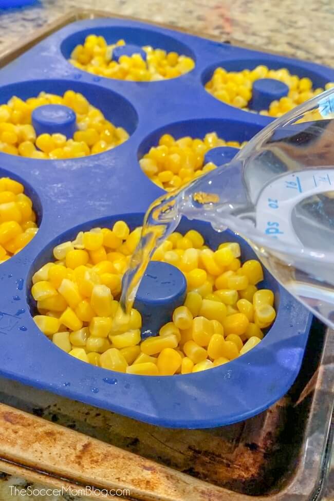 pouring water into donut pan with corn to make frozen chicken treats