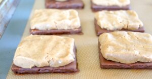 covering chocolate graham crackers with a peanut butter layer