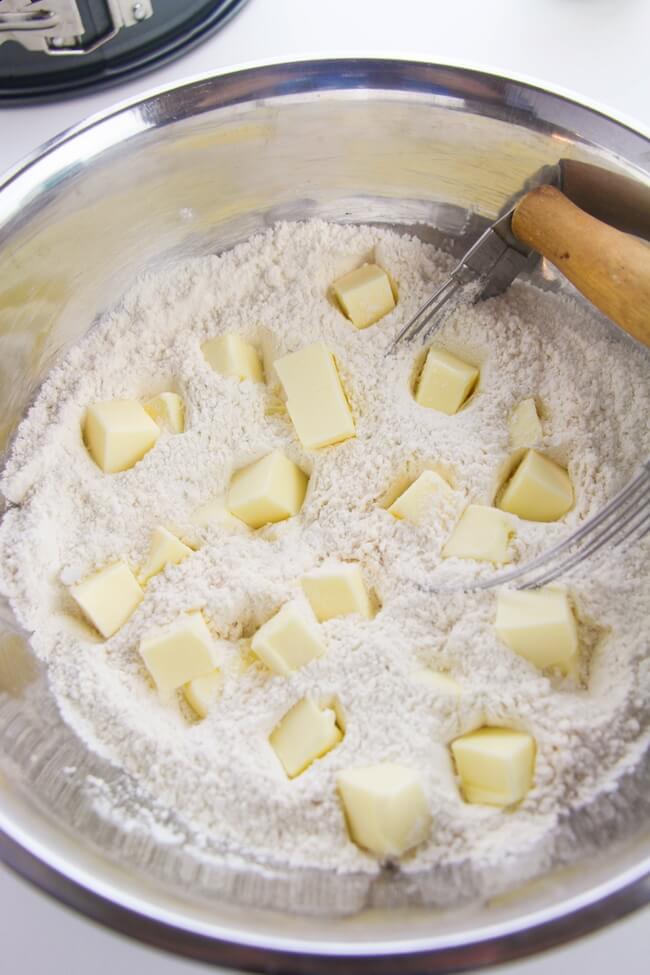 breaking up cubes of butter into biscuit flour