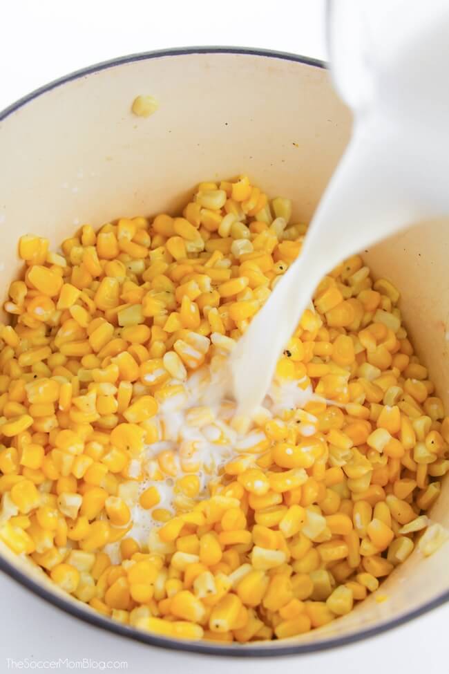 pouring milk into a dutch oven of corn kernels
