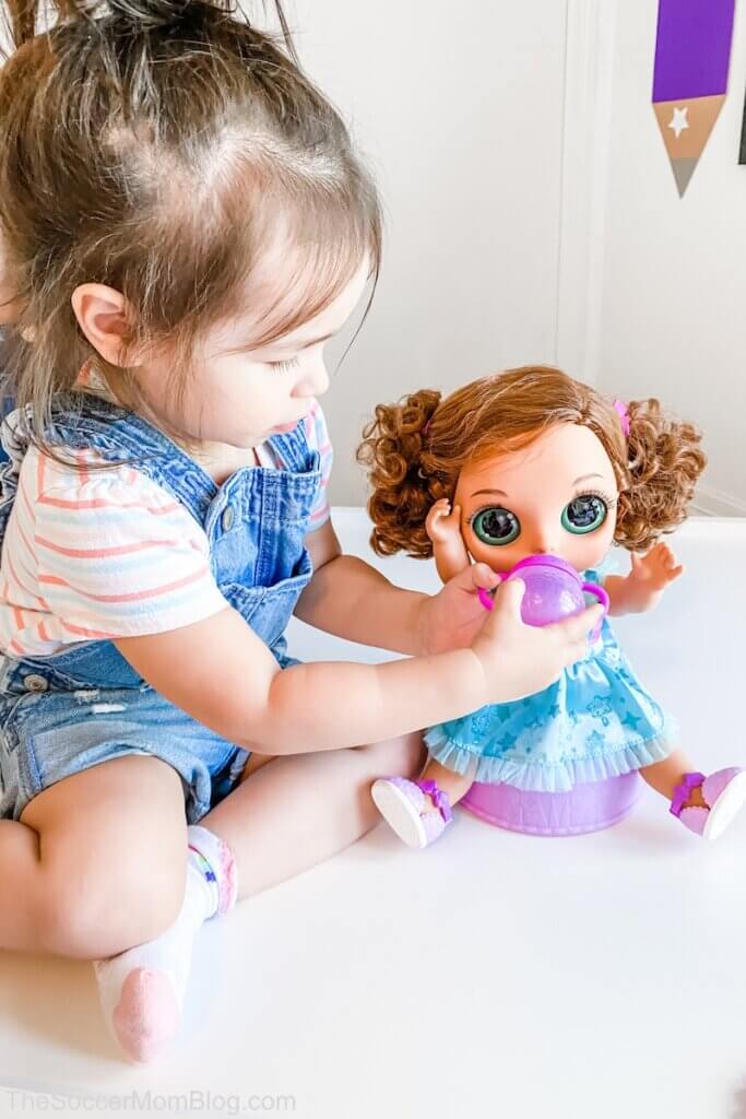 little girl giving baby doll a bottle