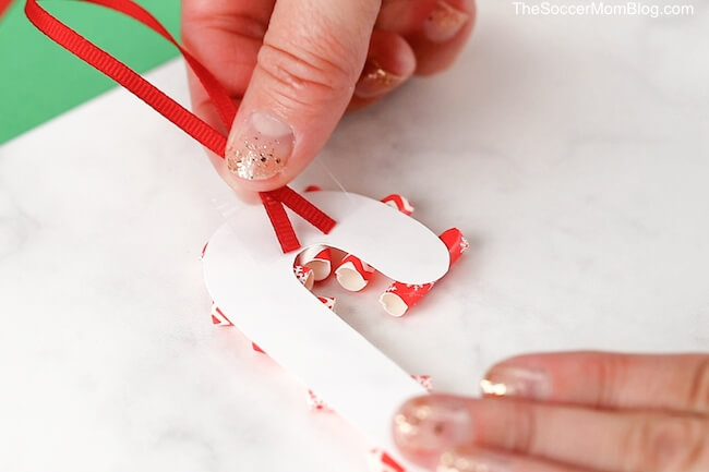 taping a loop of ribbon on the back of a homemade Christmas ornament
