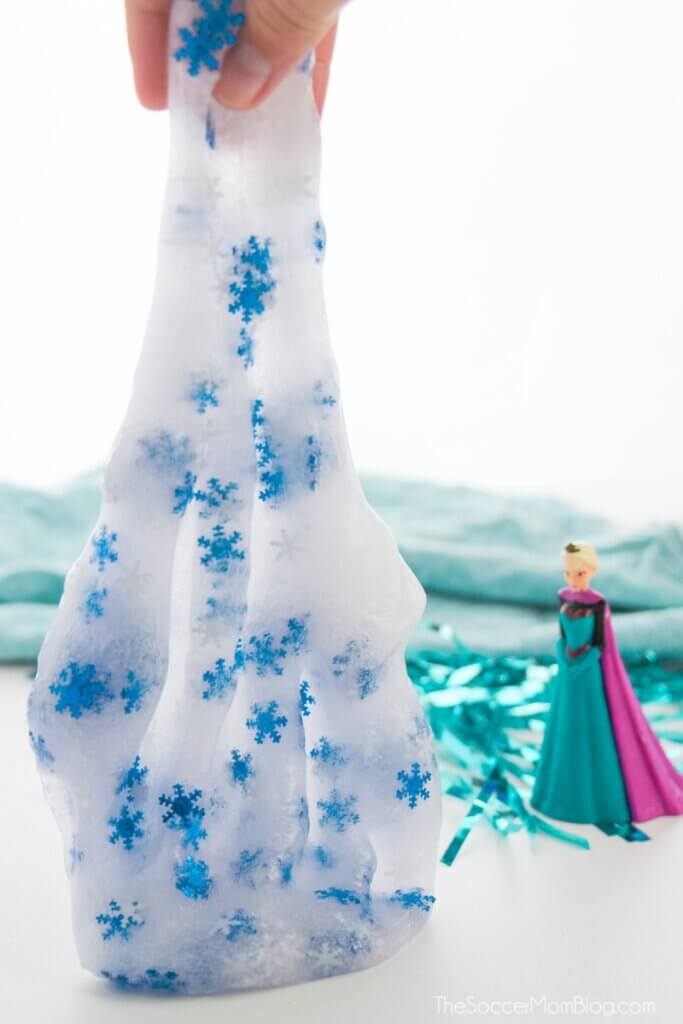 stretching frozen slime with snowflake glitter next to Elsa doll