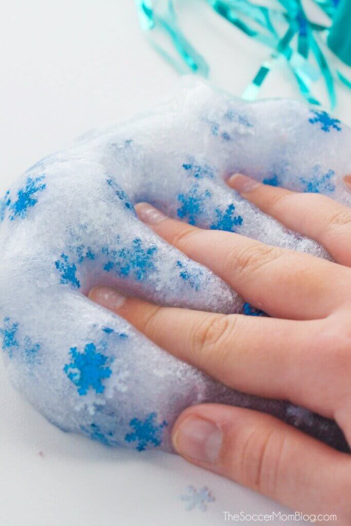 little kid's hand squishing frozen themed slime with snowflake glitter