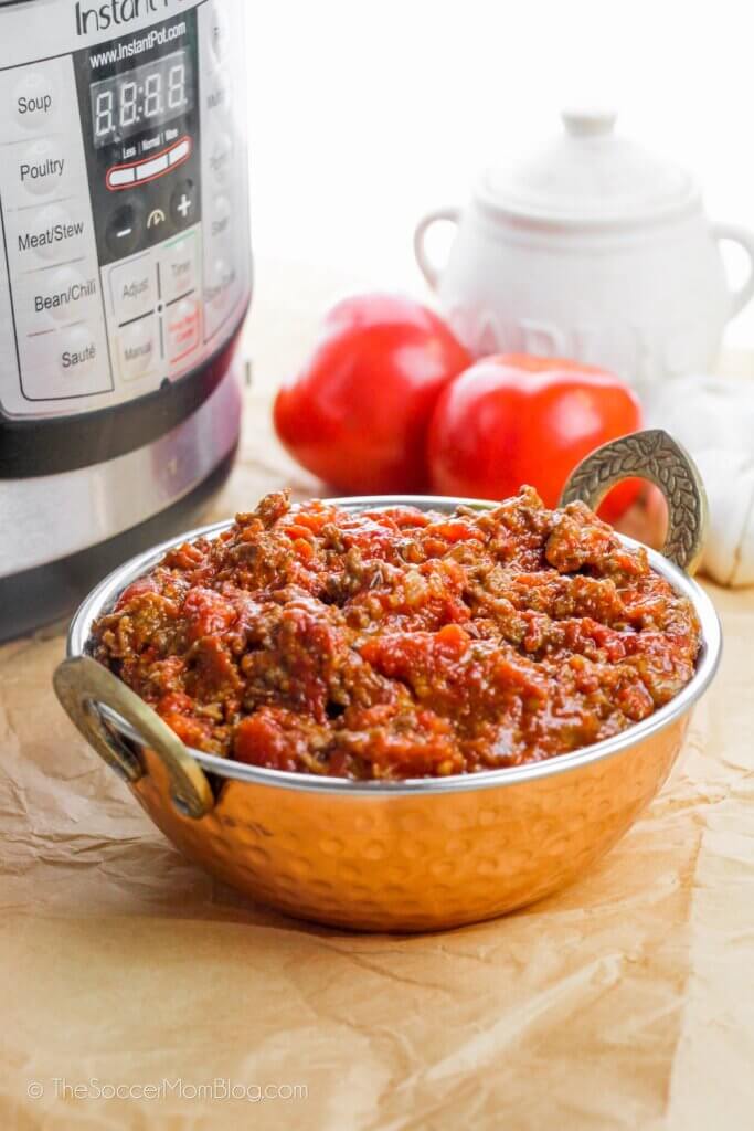 Fresh Instant Pot Meat Sauce in a metal bowl, tomatoes in background