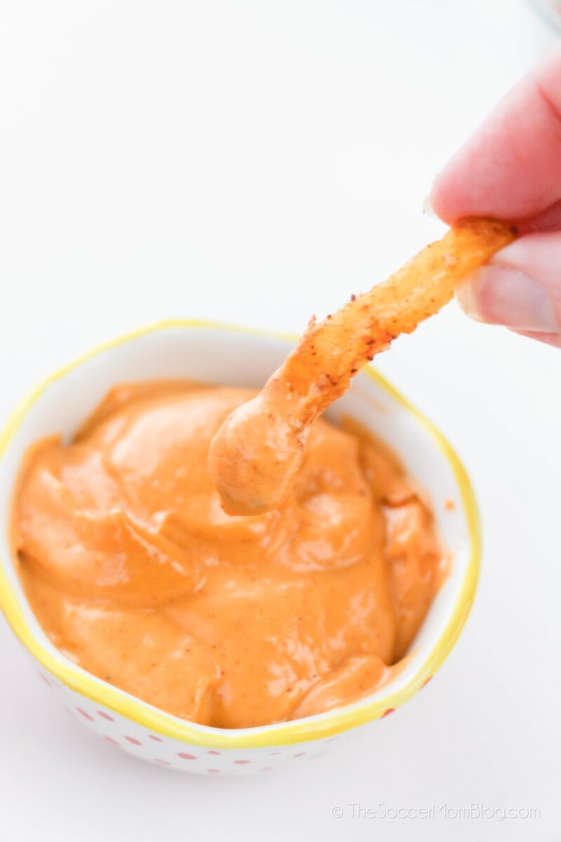 dipping French Fry in spicy mayo