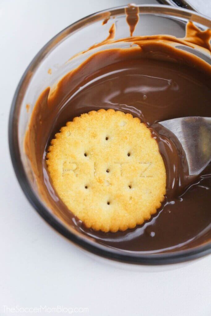dipping a Ritz cracker in melted chocolate