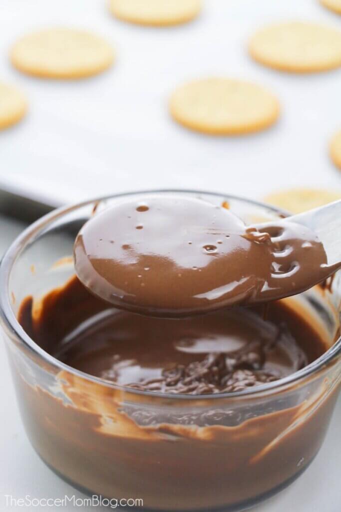 dipping a Ritz cracker in melted chocolate
