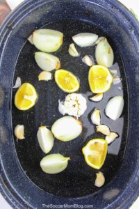 Water, onions, lemon, and garlic in a roasting pan