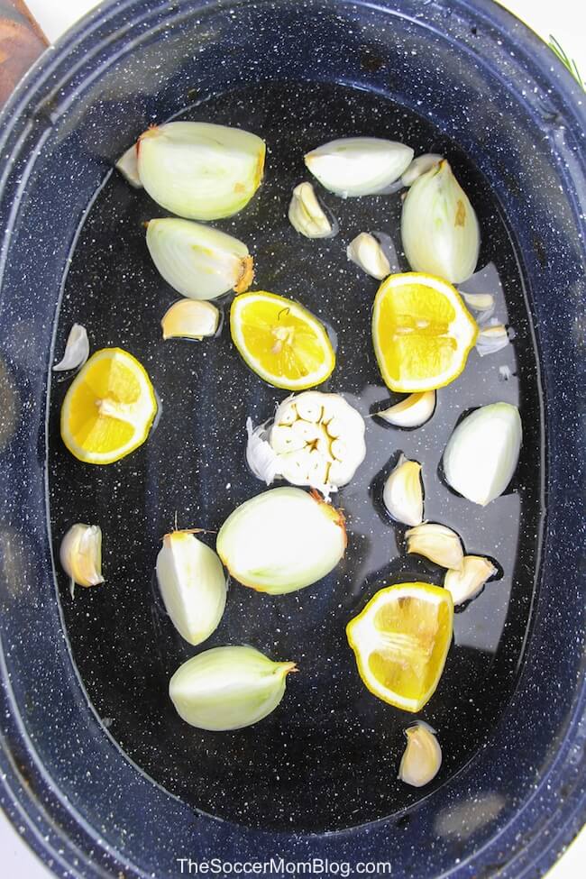 water, onion quarters, lemon wedges, and garlic cloves in roasting pan