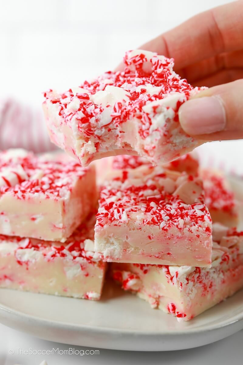 picking up a square of white chocolate peppermint fudge, with a bite missing