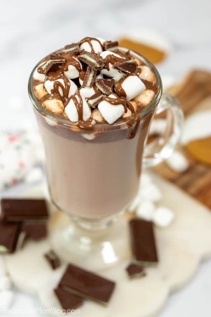 mug of mint hot chocolate with marshmallows and chocolate syrup on top