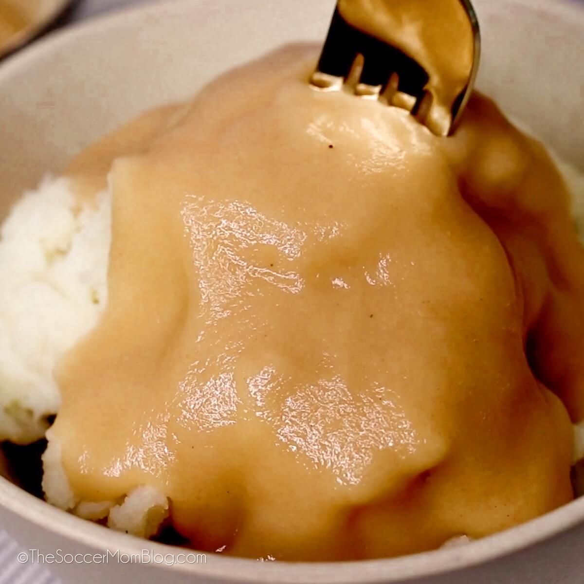 fork in a bowl of mashed potatoes and gravy.