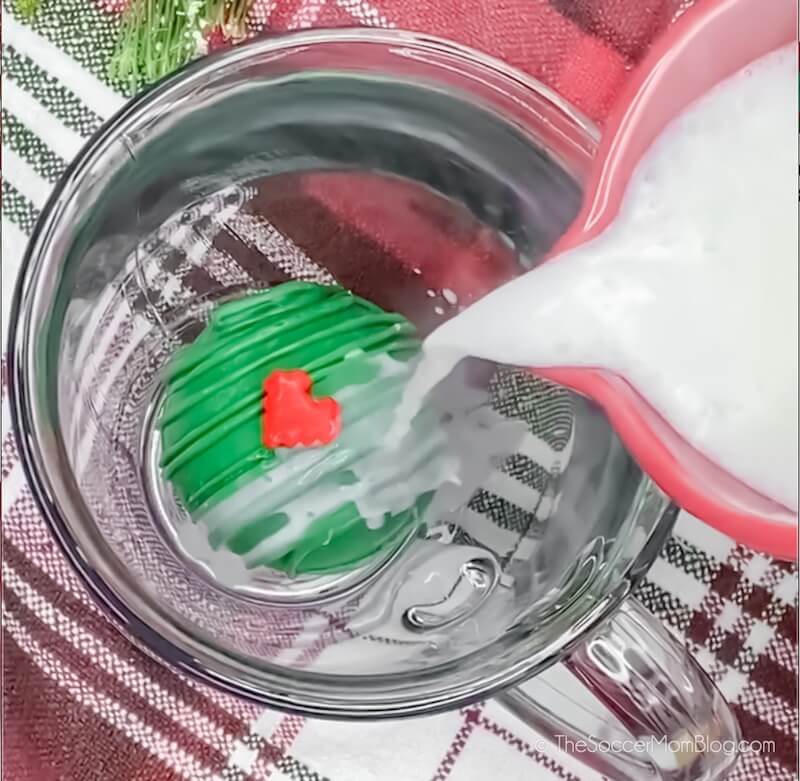pouring milk on top of a Grinch hot cocoa bomb