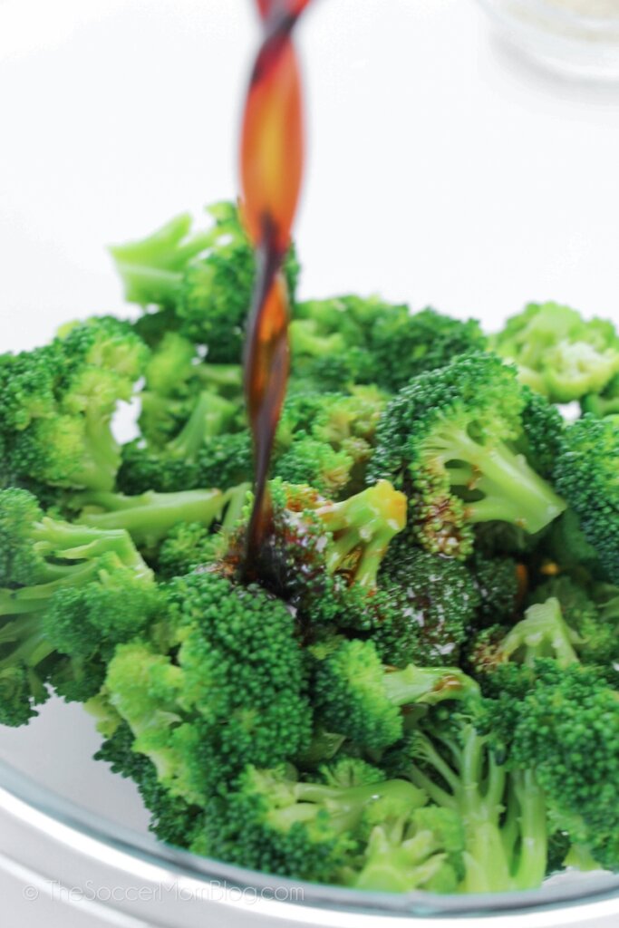 pouring garlic sauce on top of raw broccoli florets