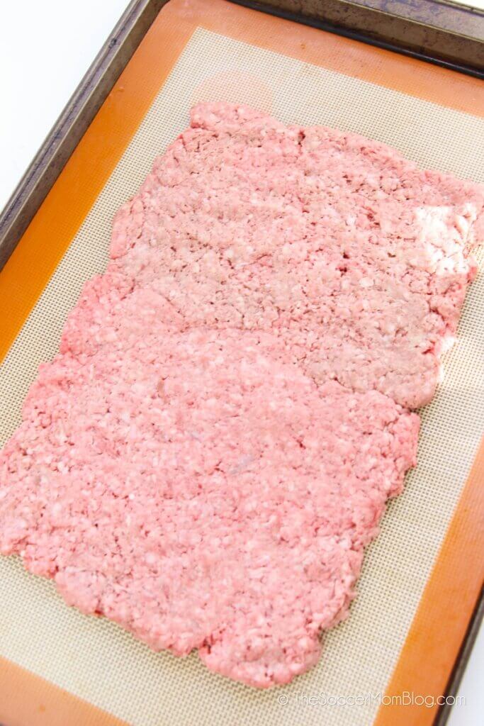 hamburger meat pressed onto baking sheet