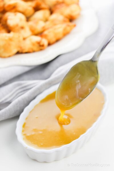 spoon dipping into homemade honey mustard sauce with copycat Chick-Fil-A nuggets in background