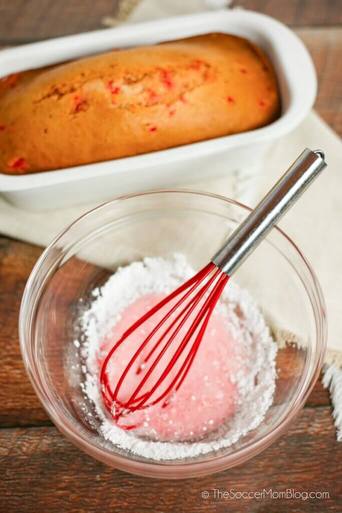 mixing cherry icing with loaf of freshly baked cherry bread in background