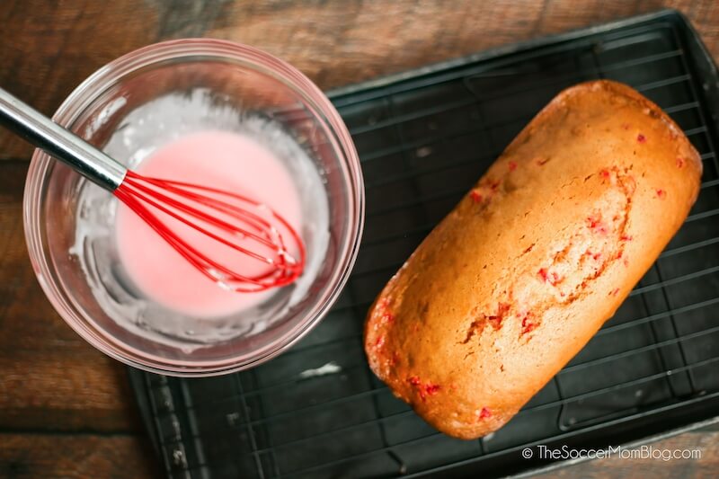 fresh baked cherry bread on wire rack next to a bowl of cherry glaze