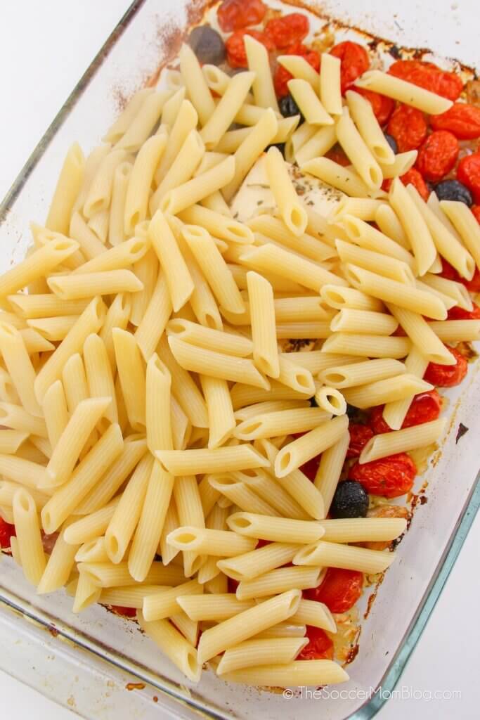 adding cooked pasta to feta cheese and tomatoes