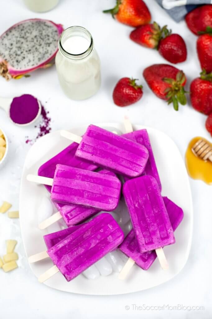 Dragon Fruit Popsicles piled on a plate surrounded by fruits