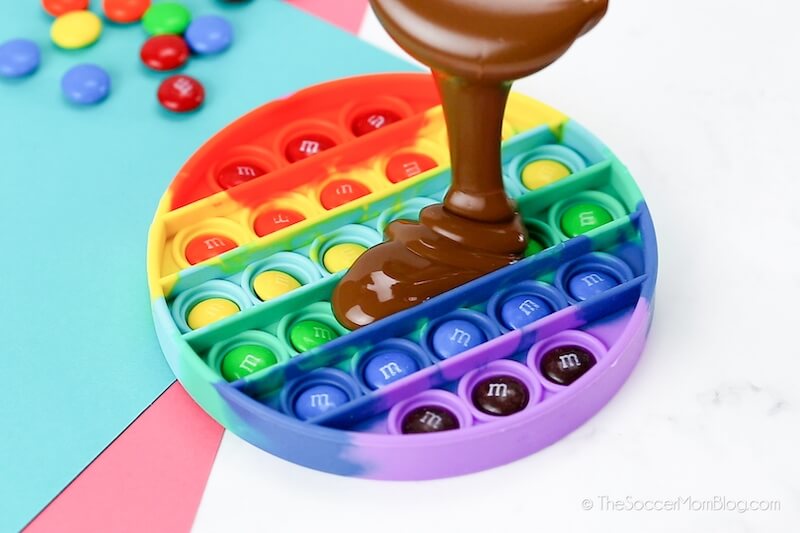 pouring melting chocolate in a pop-it mold