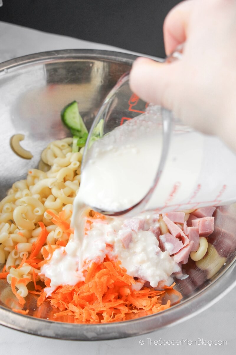 pouring dressing into pasta salad