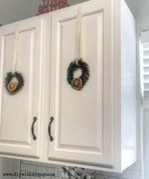 mini wreaths hanging on kitchen cabinets