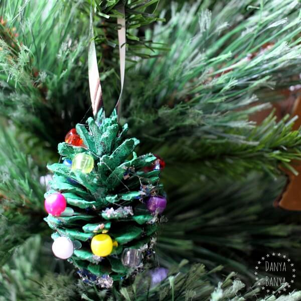 pinecone decorated to look like Christmas tree with beads