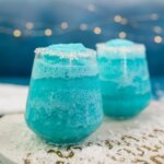 two icy blue Jack Frost winter cocktails, with blue background