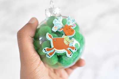 green pom-pom filled ornament with reindeer sticker on front