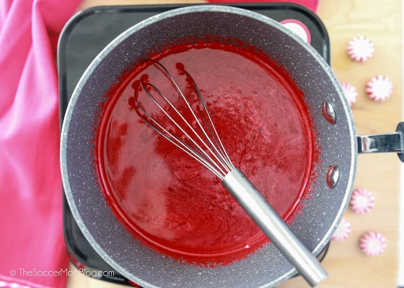 mixing red jello in a saucepan