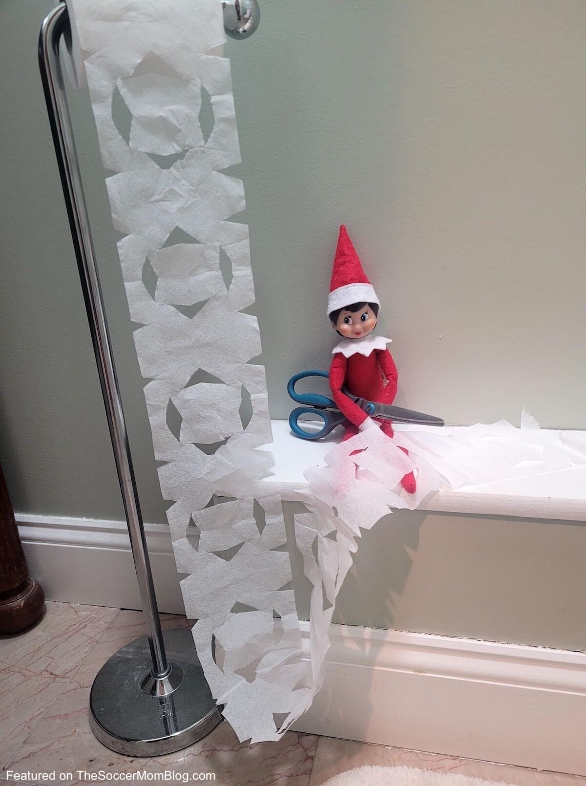 elf cutting paper snowflakes out of toilet paper