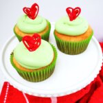 platter of Grinch cupcakes with green frosting and red candy hearts