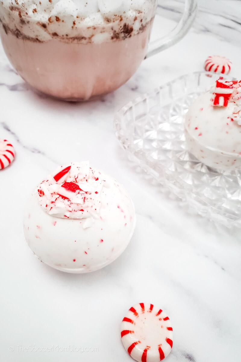 Peppermint hot cocoa bombs with a mug of hot cocoa