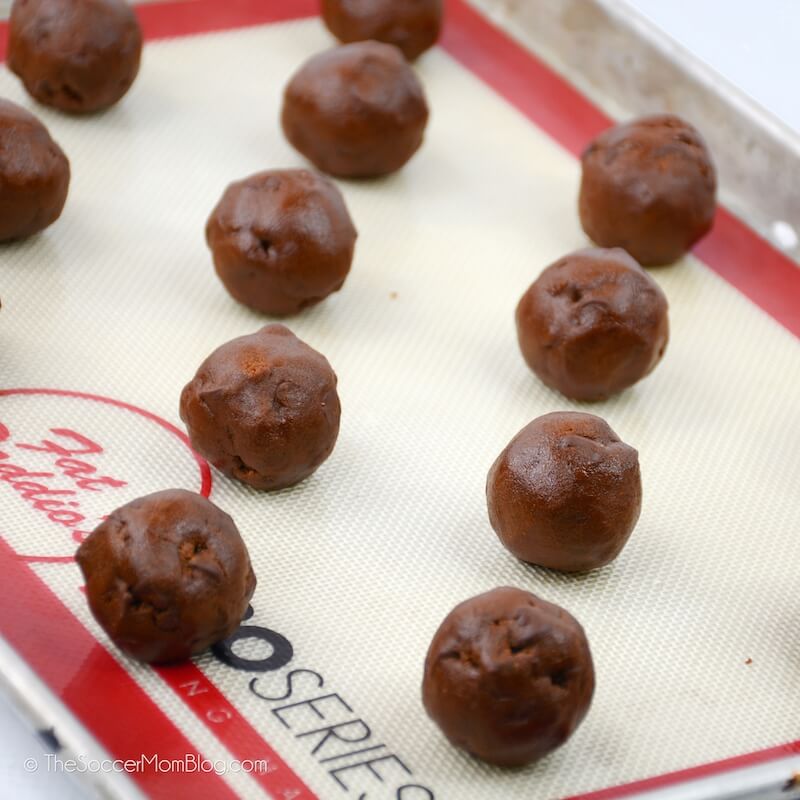 balls of chocolate cookie dough on baking sheet with silicone mat