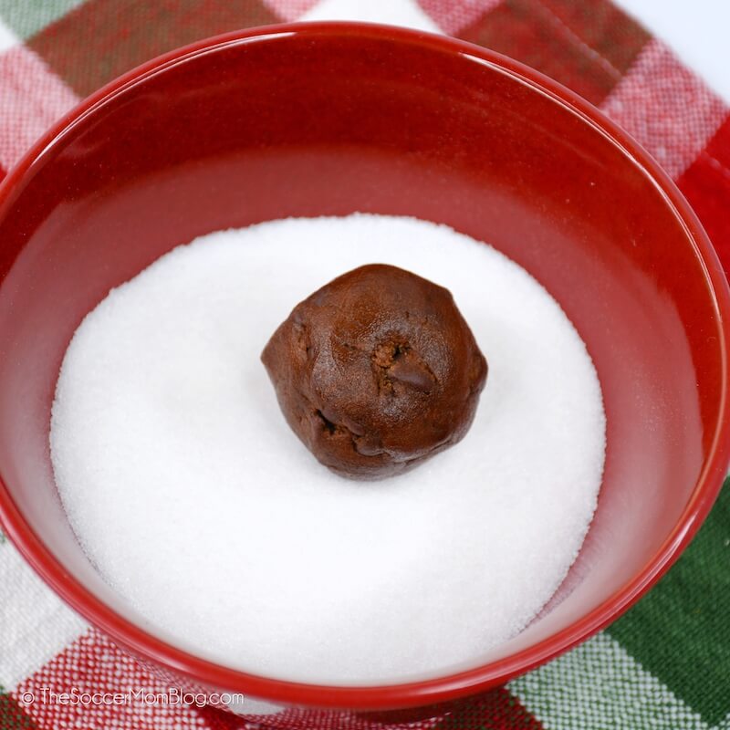 ball of chocolate cookie dough in a bowl of granulated sugar