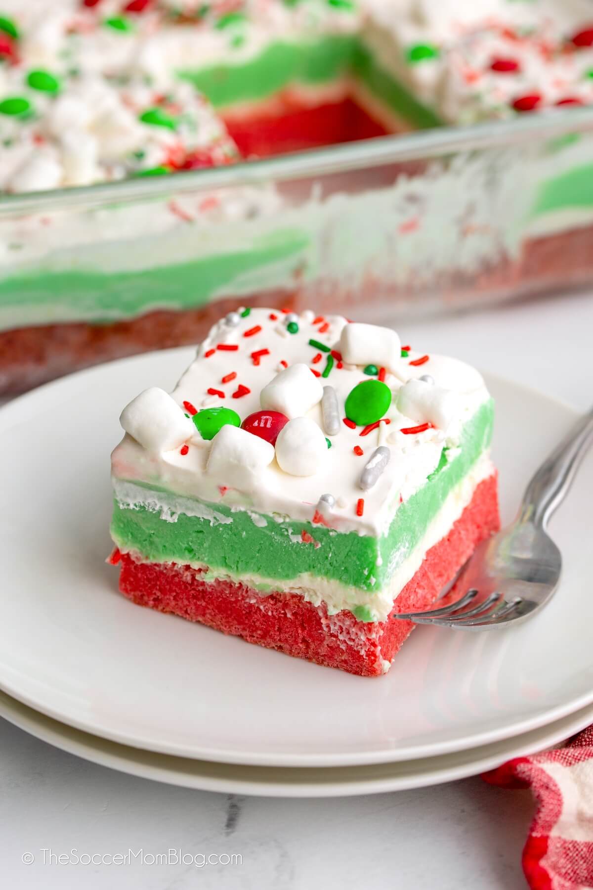 red and green Christmas lasagna dessert, slice on plate and full pan in background