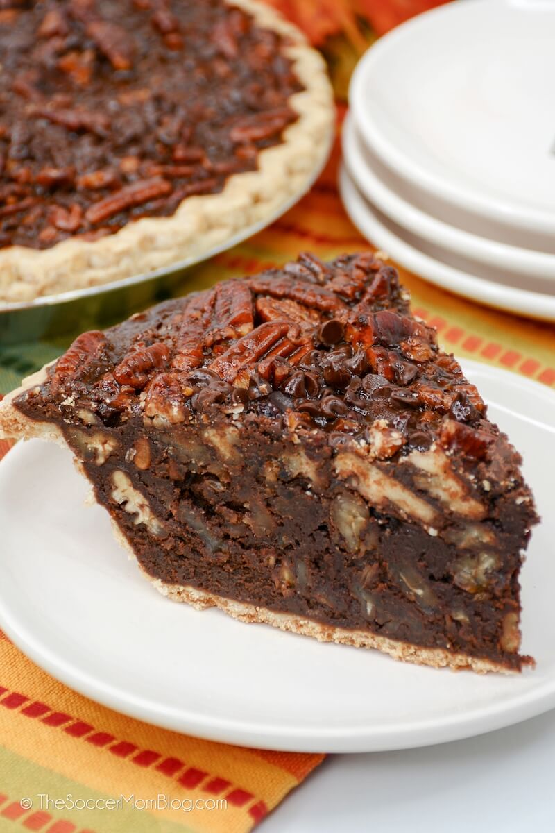 close up slice of chocolate pecan pie, with fudge filling topped with pecan halves