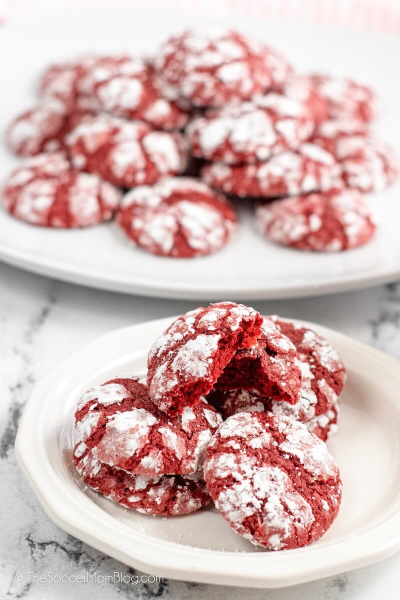two plates filled with red velvet cookies, with powdered sugar